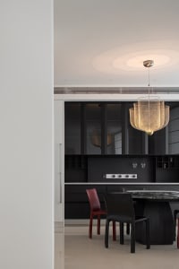 A modern kitchen with black wood furniture, metallic mesh pendant light, and marble countertop.