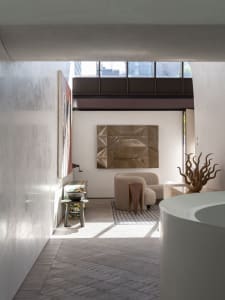 Modern living room featuring concrete walls, wooden flooring, metal accents, and upholstered furniture.