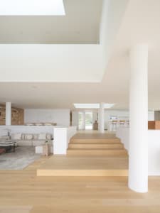 Light wood floor and minimalist living room with white furniture and a sky window