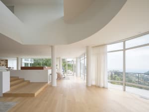 A modern living room with a wooden floor and white curtains.