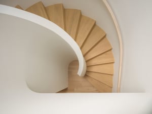 Modern, wooden staircase with white walls in a floor plan view.
