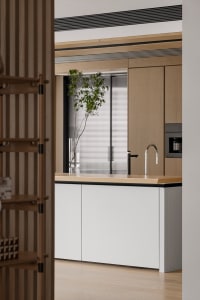 Modern minimalist kitchen with wood finishes and a white island featuring a sink and a plant.