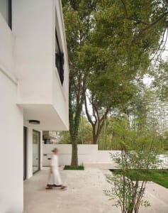 A modern house with a concrete exterior, surrounded by greenery.