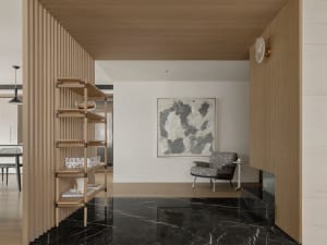 A modern living room features a black marble floor, wooden accents, and a cozy armchair.