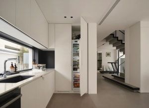 A modern, minimalist kitchen with white cabinets, a concrete countertop, and a black stove top oven.
