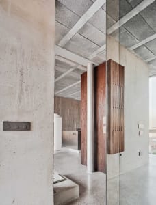 A modern living room with concrete walls, wooden accents, and open space.