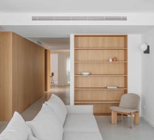 A modern minimalist living room featuring wooden shelves and a comfortable couch.