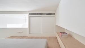 Bedroom with white walls, wooden floor, and minimalist furniture.