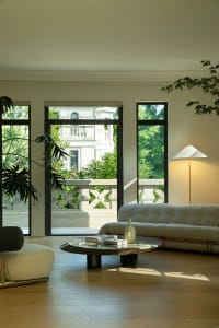 A modern minimalist living room featuring concrete, glass, and wooden elements.