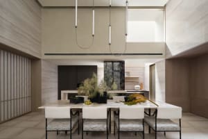 A modern dining room with marble table and chairs, concrete walls, and pendant lights.