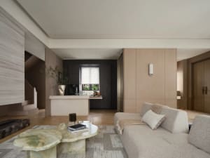 Modern minimalist living room with beige walls, wooden flooring, and a light-colored sofa.