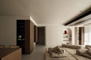 A modern living room with minimalist design, featuring a tan sectional sofa, white walls, and wooden furniture.