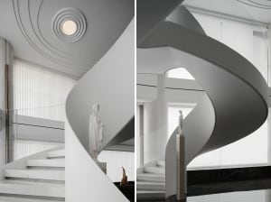 Modern interior staircase with white concrete spiral design, featuring a statue and vertical blinds.