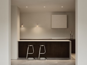 Modern and minimalist residential kitchen with sleek furniture and white countertops.
