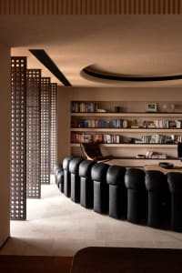 A modern living room featuring black leather upholstered furniture and a collection of books on shelves.