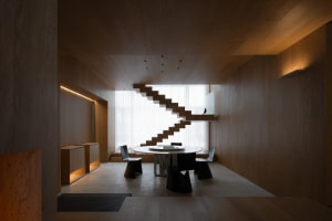 A modern interior space featuring wooden paneling, a staircase, and a dining area with a round table and chairs.