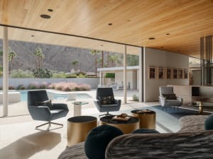 Modern living room featuring a wood-paneled ceiling, grey furniture, and a view of a swimming pool and outdoor area.