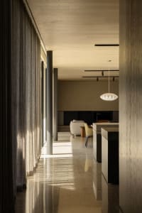 A modern living room with concrete walls, a white sofa, and a pendant light hanging from the ceiling.