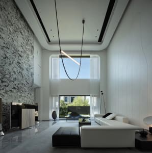 Modern living room with marble accents, high-ceiling, and large windows.