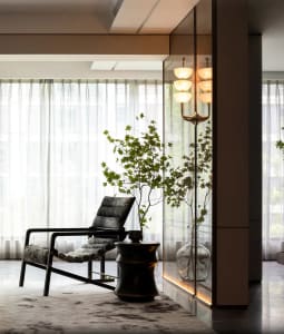 Modern living room with a glass window, black armchair, and potted plant.
