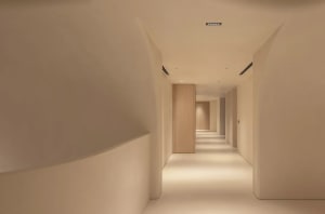A minimalist corridor with concrete walls and floors, featuring clean lines and simple design elements.