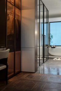 Modern bathroom featuring wooden flooring and a glass-enclosed bathtub.