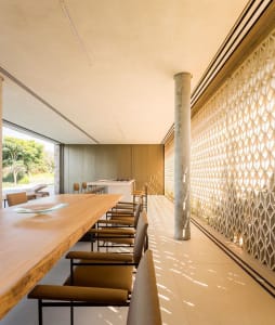 Modern dining area featuring a wooden table and concrete columns with a geometric pattern.
