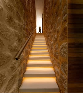 A modern staircase with illuminated steps and concrete walls.