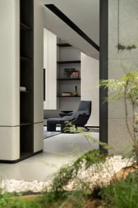 Modern living room with concrete walls and floor, featuring minimalist furniture and greenery.
