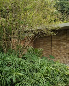 An outdoor landscape featuring a stone wall and a wooden structure.