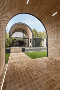 A modern architectural exterior featuring a brick walkway, concrete floor, and tiled poolside area.