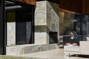 Modern, minimalist outdoor living space featuring stone, concrete, and metal materials.
