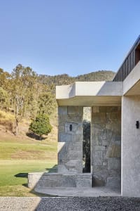 Modern residential exterior with granite entryway, landscaped yard, and mountainous backdrop.