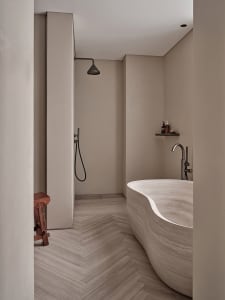 Modern minimalist bathroom featuring a freestanding marble bathtub and a shower area with minimalist design elements.