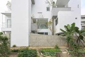 A minimalist residential building with a white exterior featuring concrete walls and a simple design.