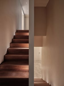 Modern staircase with dark wooden steps illuminated by soft, ambient lighting