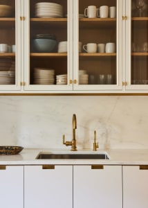 A modern kitchen featuring marble countertops and brass fixtures.