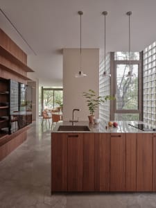 Modern residential kitchen featuring wooden cabinets, a glass-block wall, and a contemporary design.