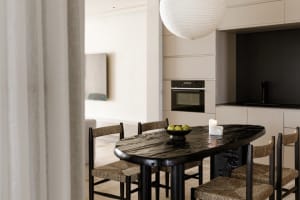 Modern residential kitchen with black marble table and woven chairs.