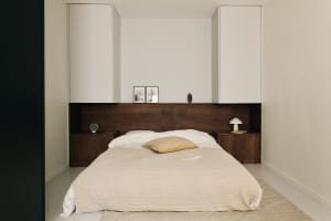 Minimalist bedroom with a wooden bed and white bedding.
