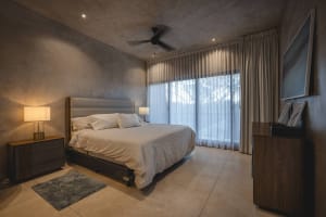 A modern minimalist bedroom with a large bed, white bedding, and a ceiling fan.
