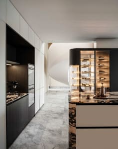 A modern kitchen with marble countertops and cabinets, featuring sleek appliances and a wine cabinet with illuminated shelves
