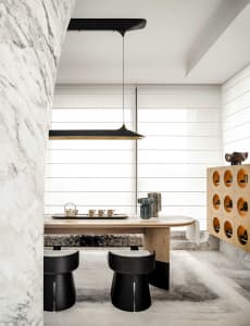 A minimalist tea room featuring a wooden table, marble walls, and ceramic tea set.