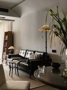 Modern minimalist living room featuring a sleek black leather sofa and a glass side table