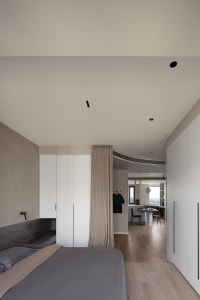 A modern bedroom with a minimalist design, featuring neutral colors and integrated storage solutions.