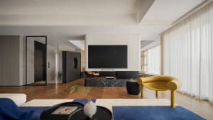 Modern living room featuring a mix of wood and other materials, with a large television screen and contemporary furniture.