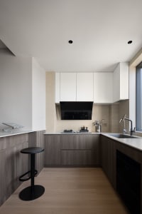 A modern minimalist kitchen featuring wood elements and a clean, white aesthetic.