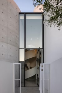 A modern residential entryway featuring glass and concrete materials.