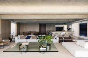 Modern living room with minimalist design, concrete walls, wooden floor, and glass furniture.
