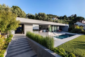 Modern residential home with concrete exterior, large sliding glass doors, and a swimming pool.